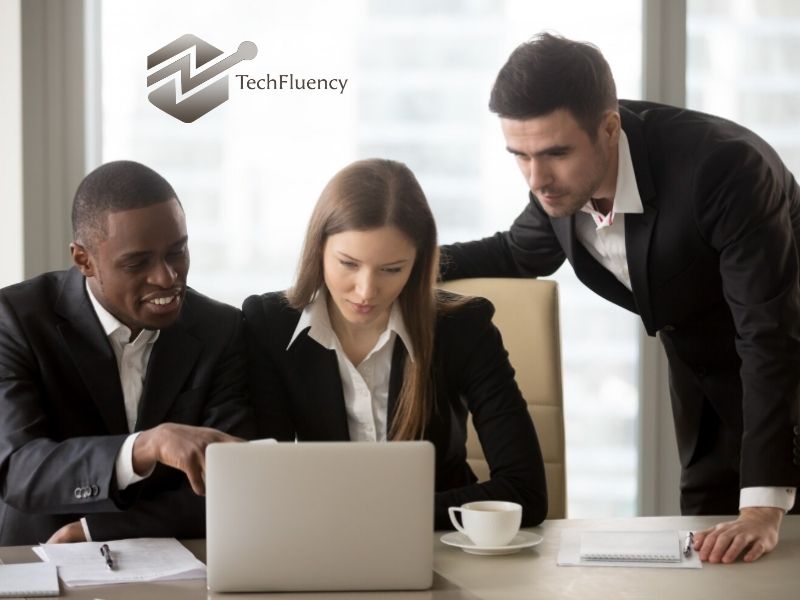 TechFluency professionals discussing project details while reviewing work on a laptop.