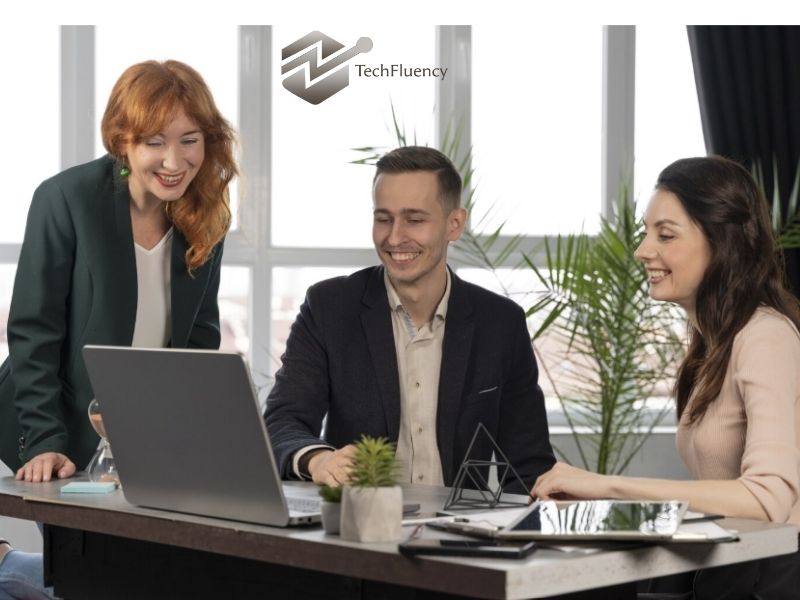 TechFluency team collaborating around a laptop during a business meeting.
